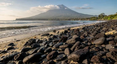 Rivage de galets volcaniques et mer calme près de Tulamben, avec le mont Agung en arrière-plan