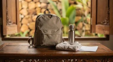Sac à dos, chemise pliée et gourde sur une table en bois devant une fenêtre ouverte à Bali